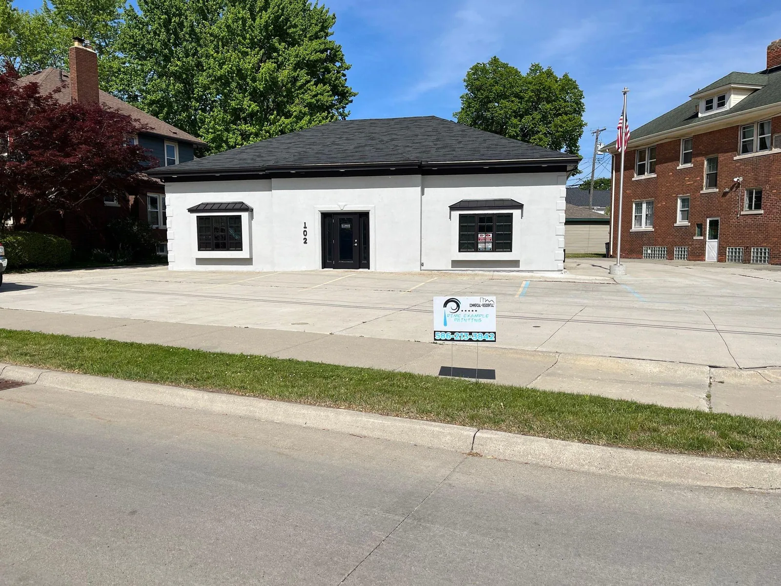Commercial building exterior repainted white with a dark roofline