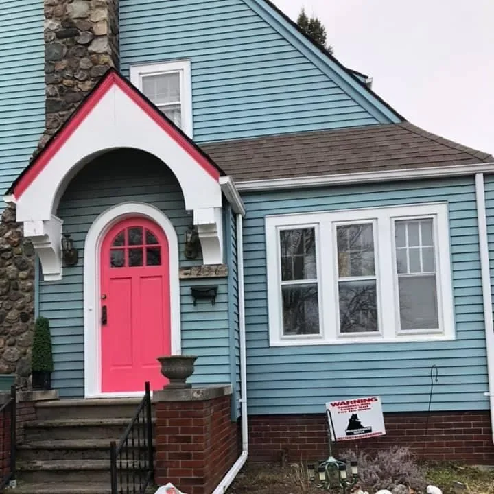 Light blue home exterior with a freshly painted red arched front door