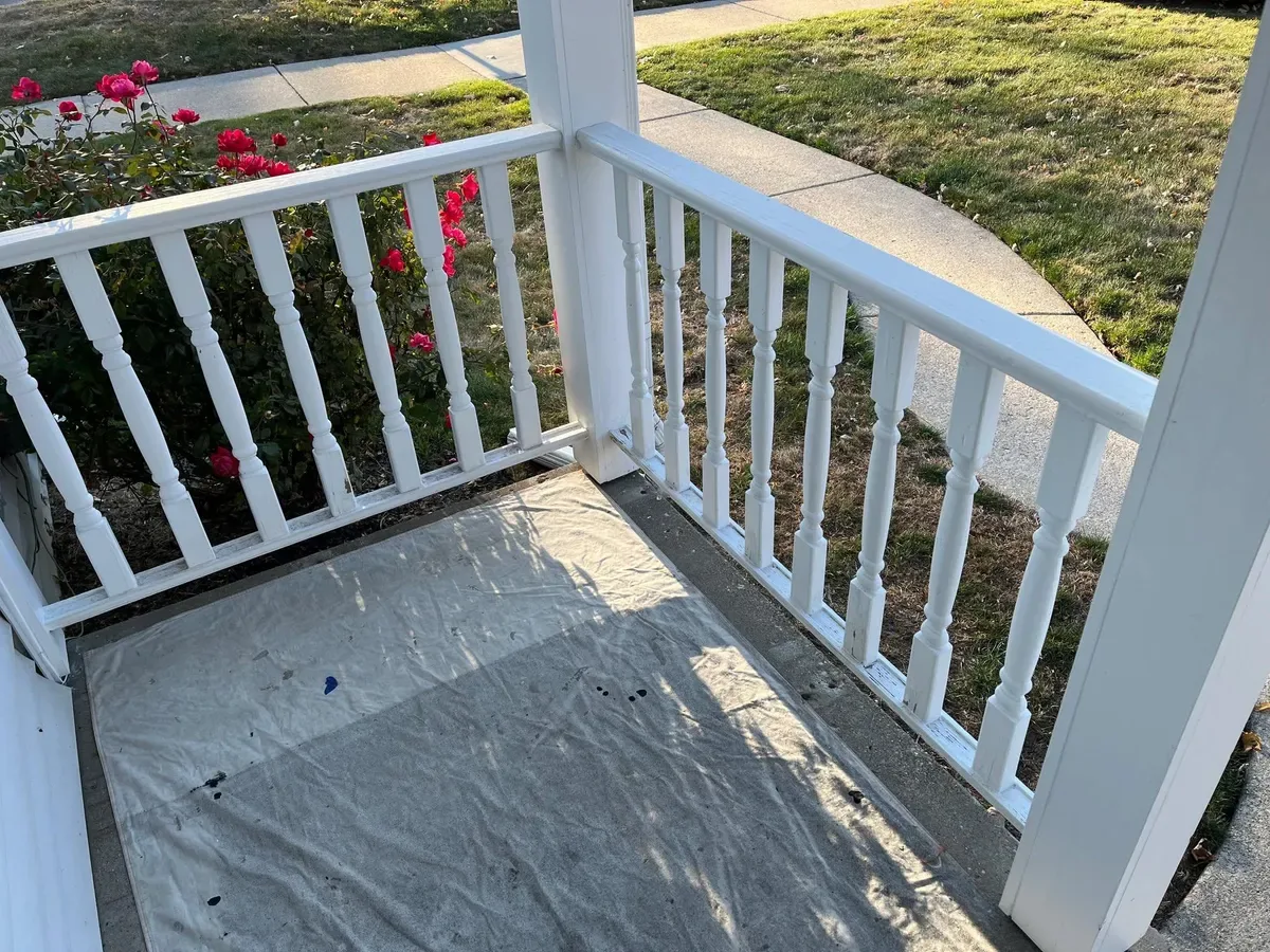 Freshly painted white deck railing with surrounding surfaces protected