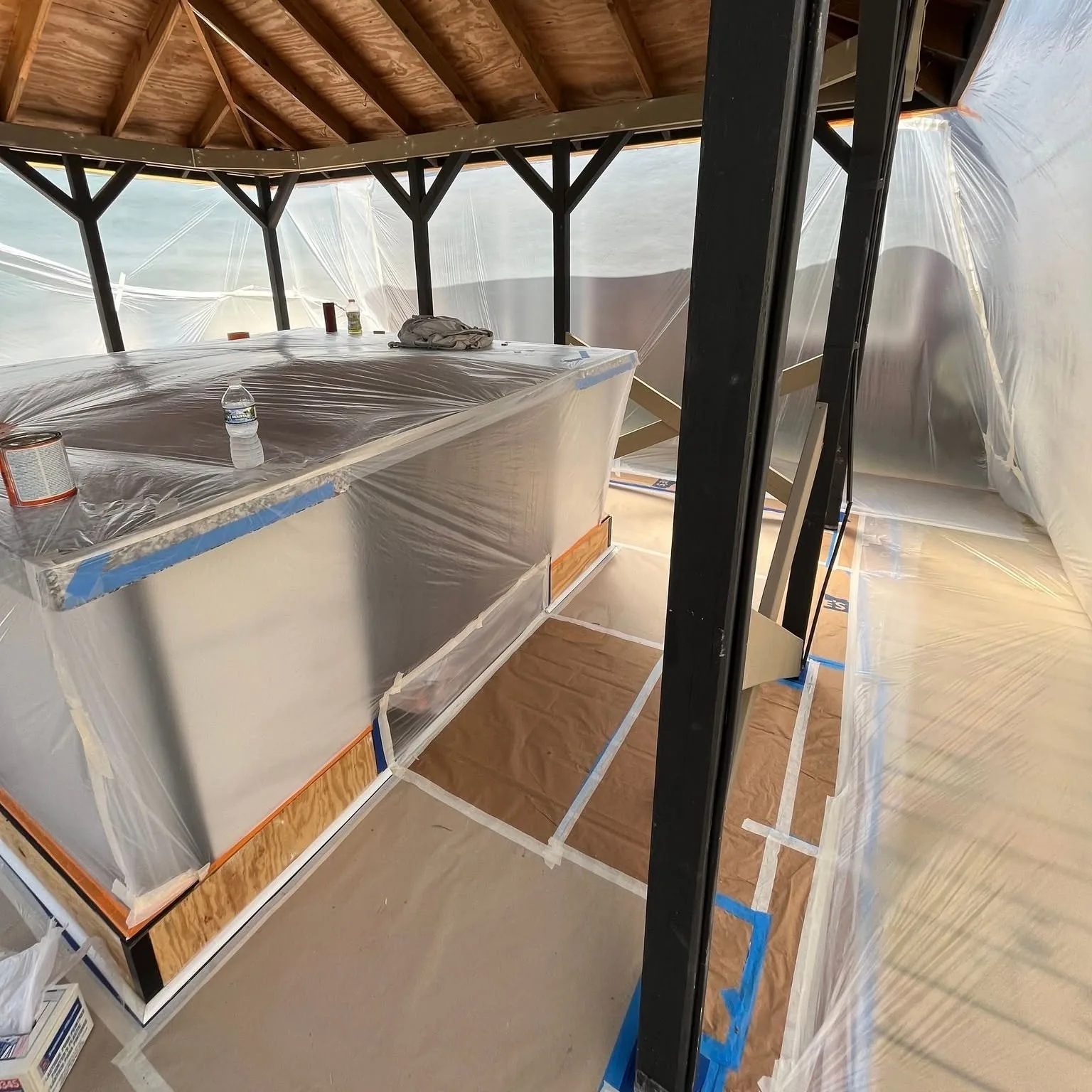 Cedar gazebo fully masked with plastic sheeting in preparation for finishing