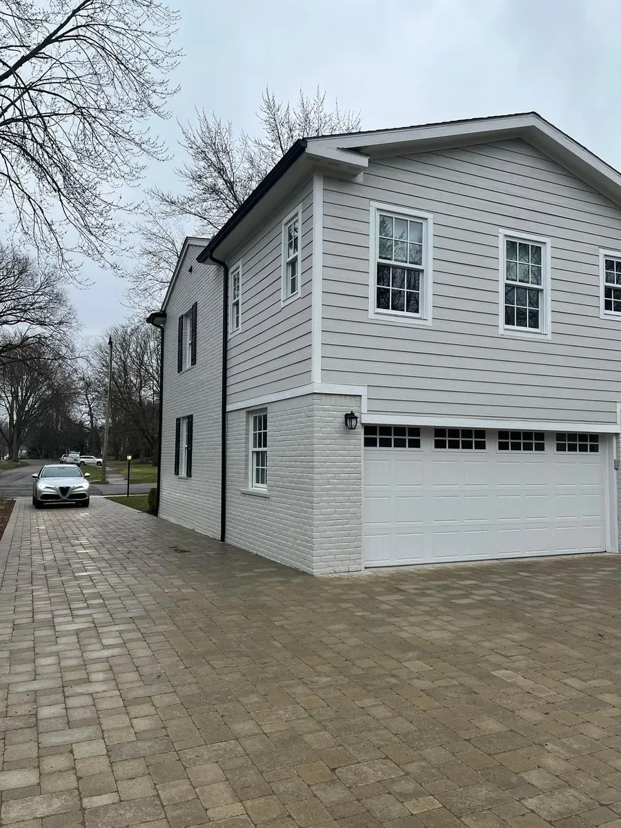 Gray two-story home with a paver driveway and repainted exterior trim